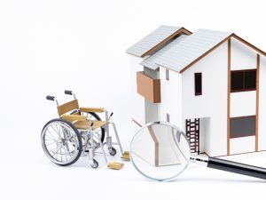 Une chaise roulante devant une maison miniature.