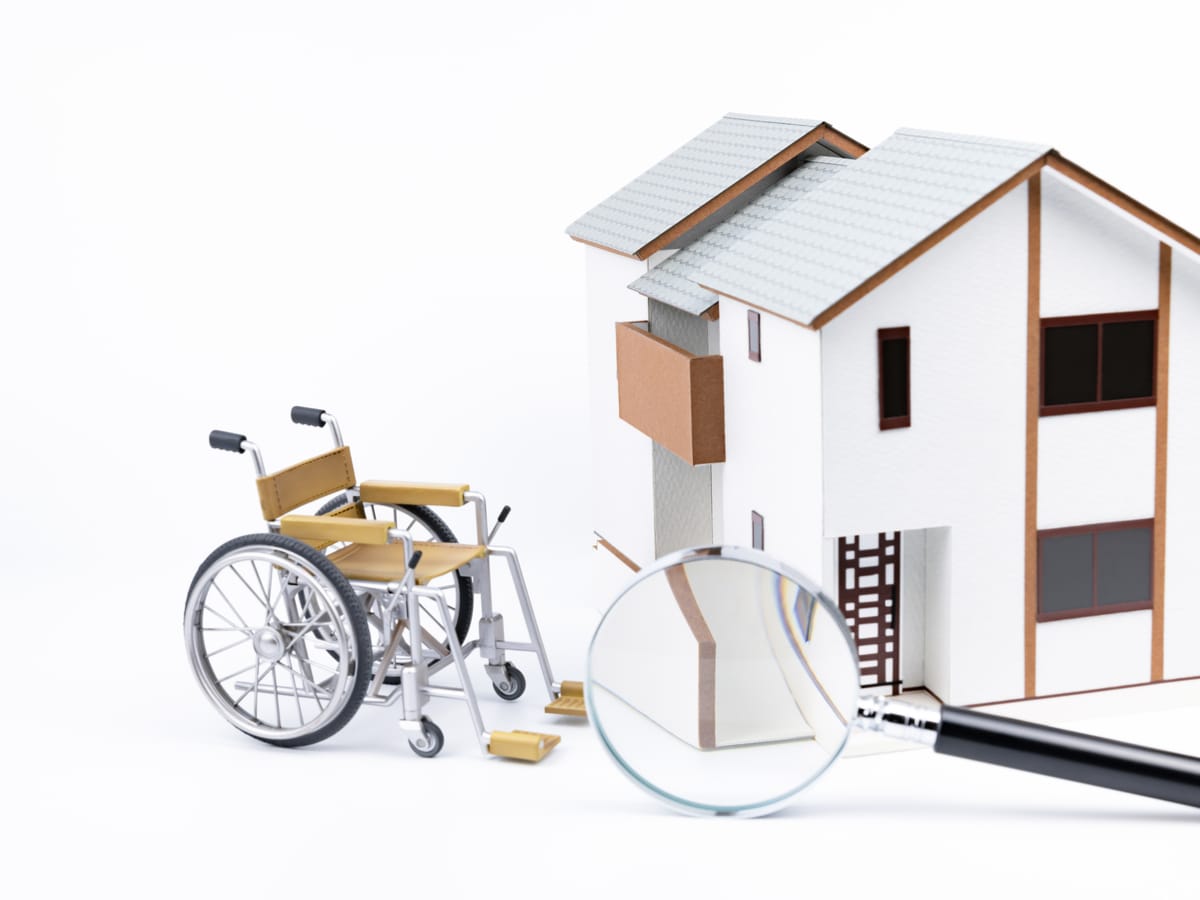 choix-equipements-aide-mobilite Une chaise roulante devant une maison miniature.